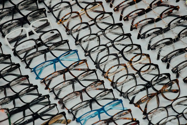 Flat lay collection of various eyeglasses and prescription frames in different shapes, styles, and sizes.