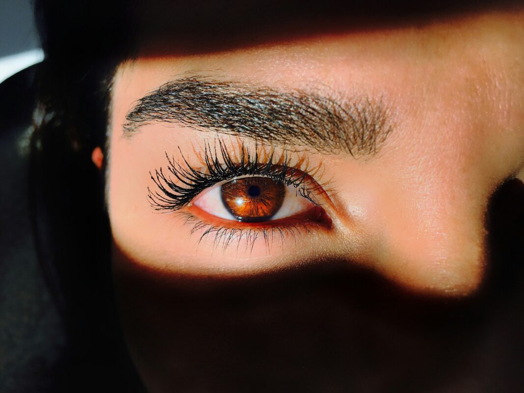 Close-up macro shot of a brown eye featuring long eyelashes and carefully applied eye makeup for contact lens wearers[cite: 12].