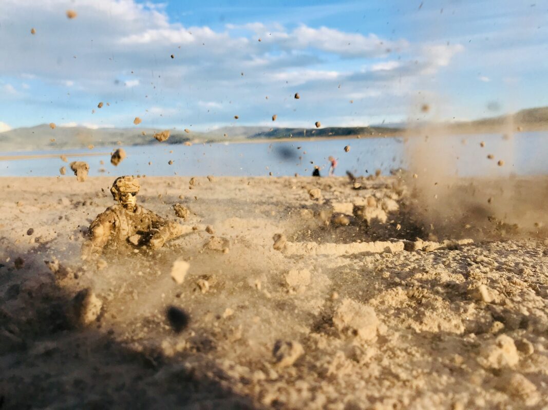 Action shot of flying sand and dust kicking up outdoors, representing debris hazards that can get trapped in the eye