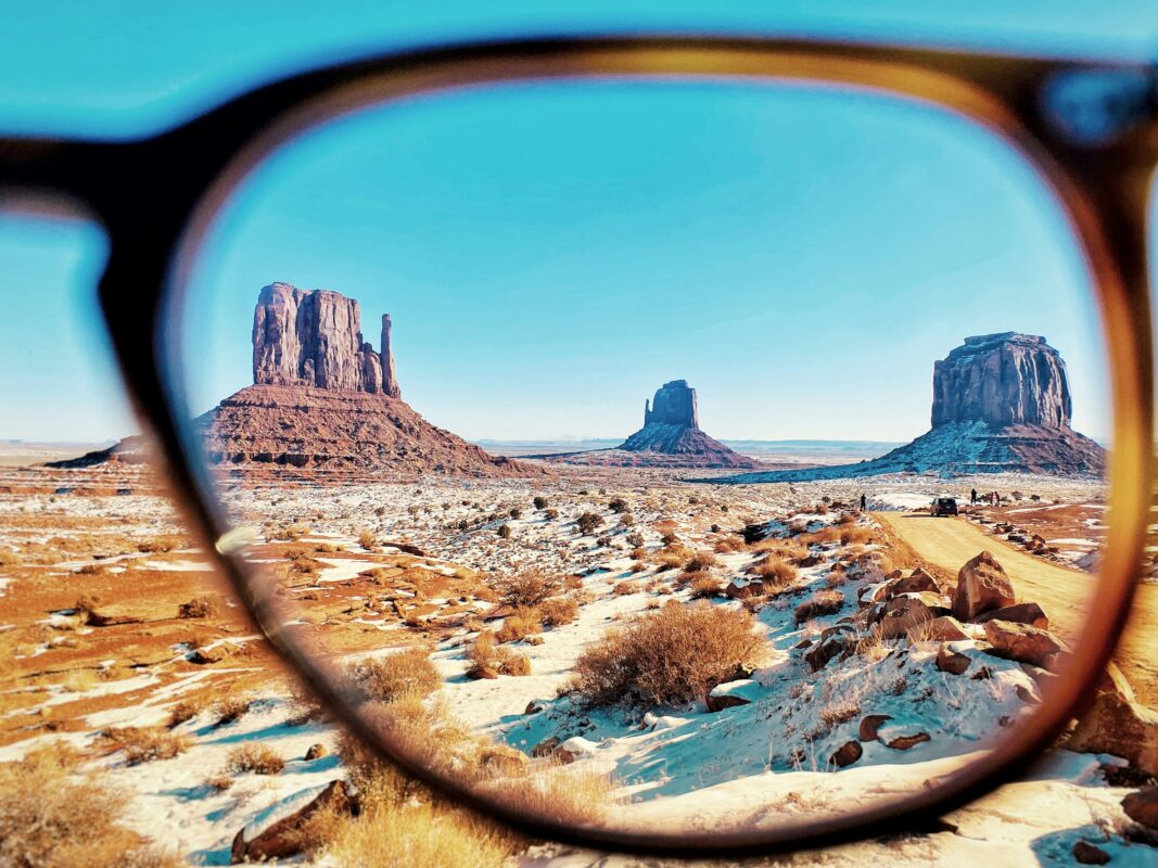 View of a snowy desert landscape with dramatic rock formations framed through a clear prescription glasses lens