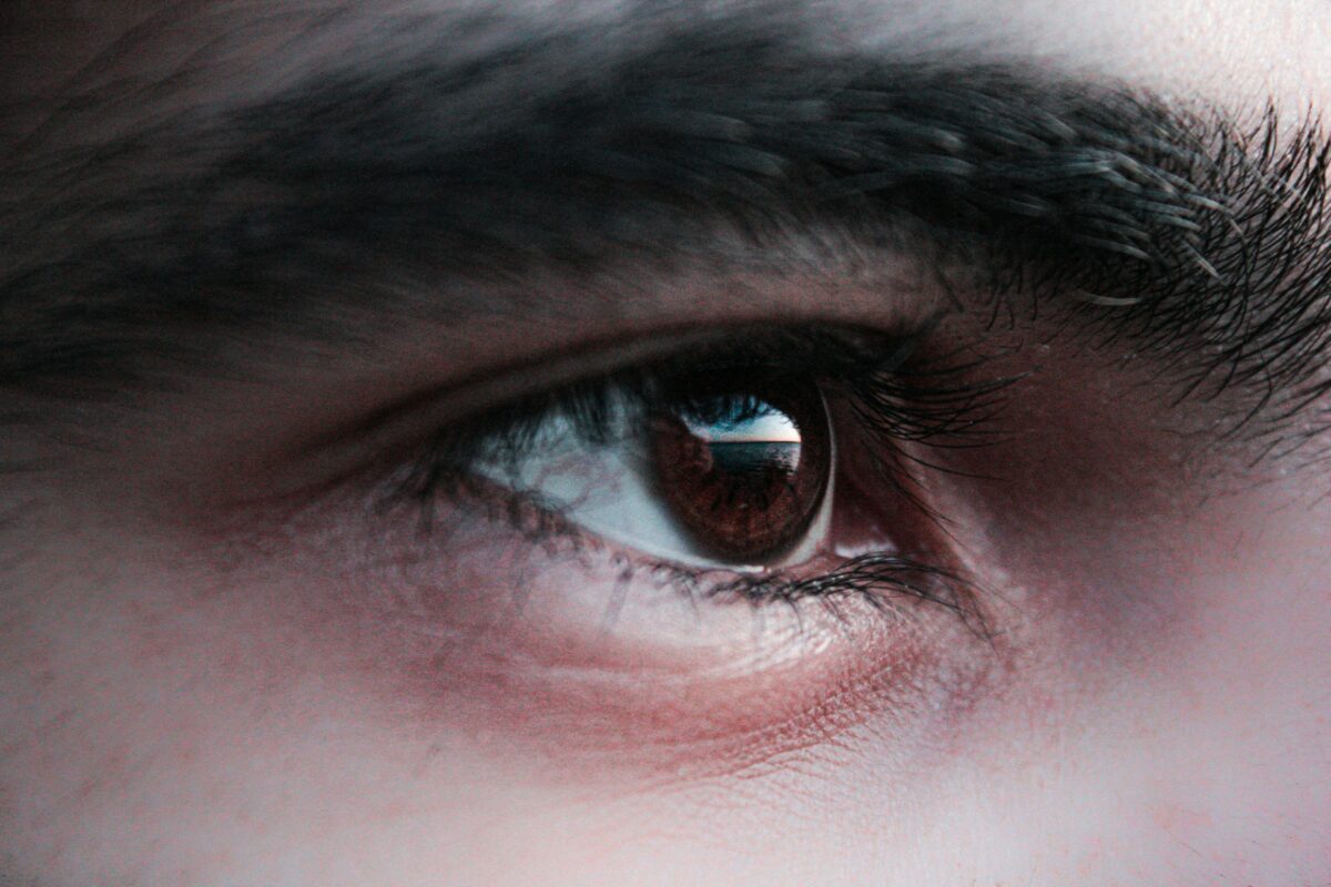 Macro close-up view of a brown human eye and eyebrow highlighting eye fatigue and eyelid twitching symptoms.
