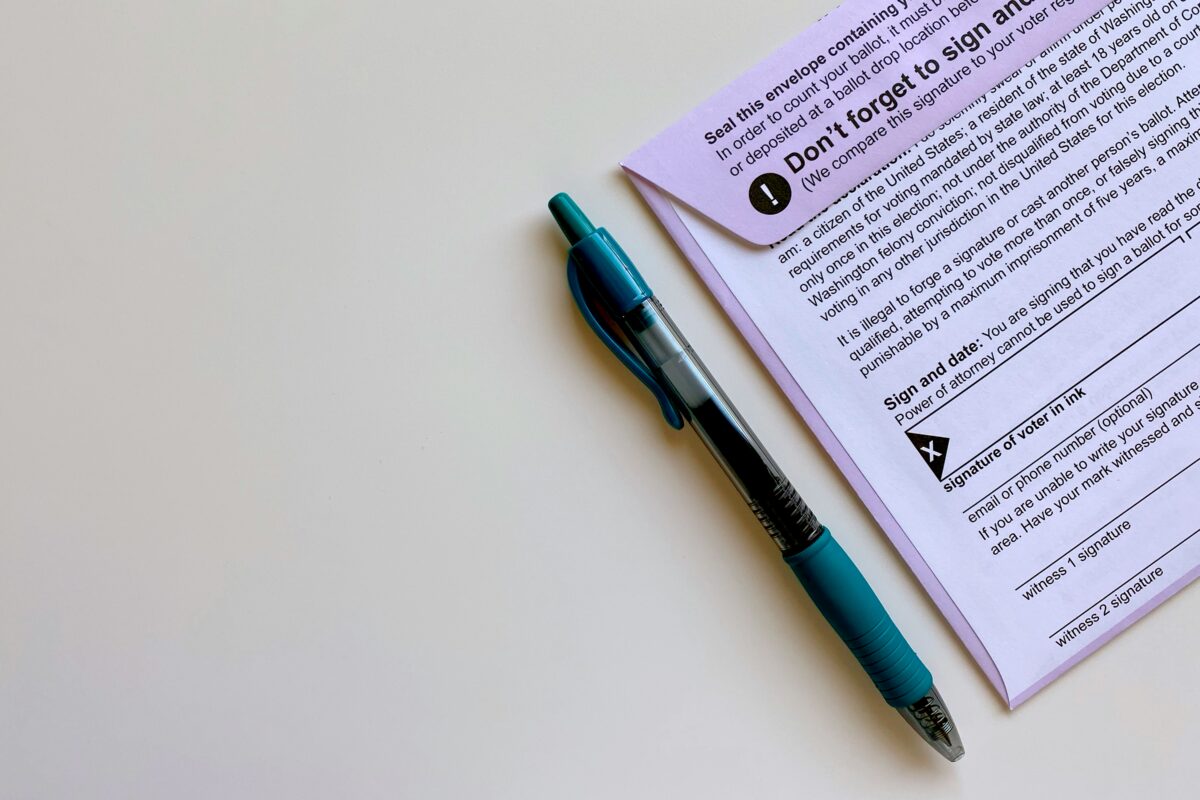 A teal pen resting on a signed official paper form and envelope, symbolizing document renewal and verification.